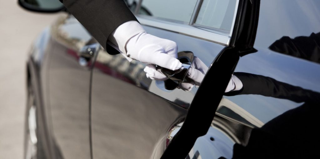 limousine door being opened by a white glove wearing chauffeur
